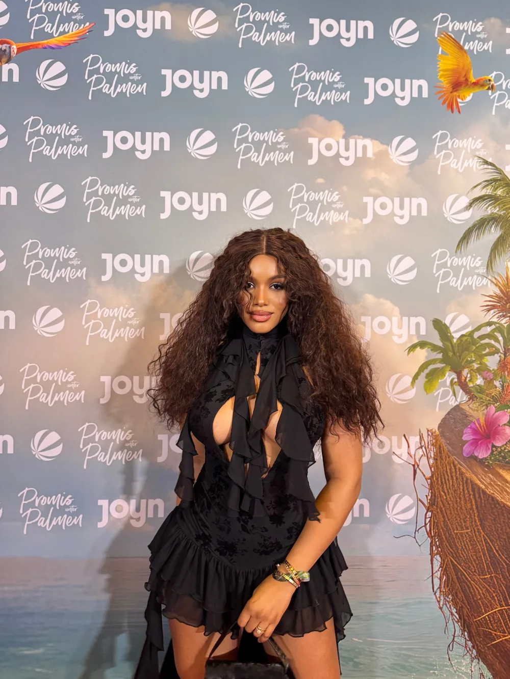 Glam-Styling mit langen Locken auf einem Event-Fototeppich